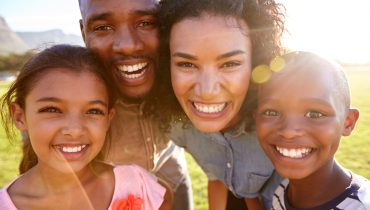laughing-black-family-outdoors-close-up-back-lit-PPCMZD4.jpg